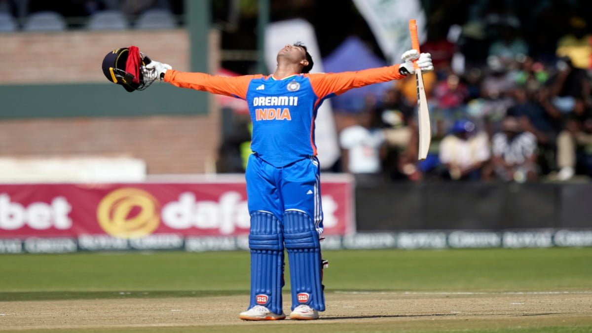 "Abhishek Sharma celebrating his T20I century with bat raised and helmet off".